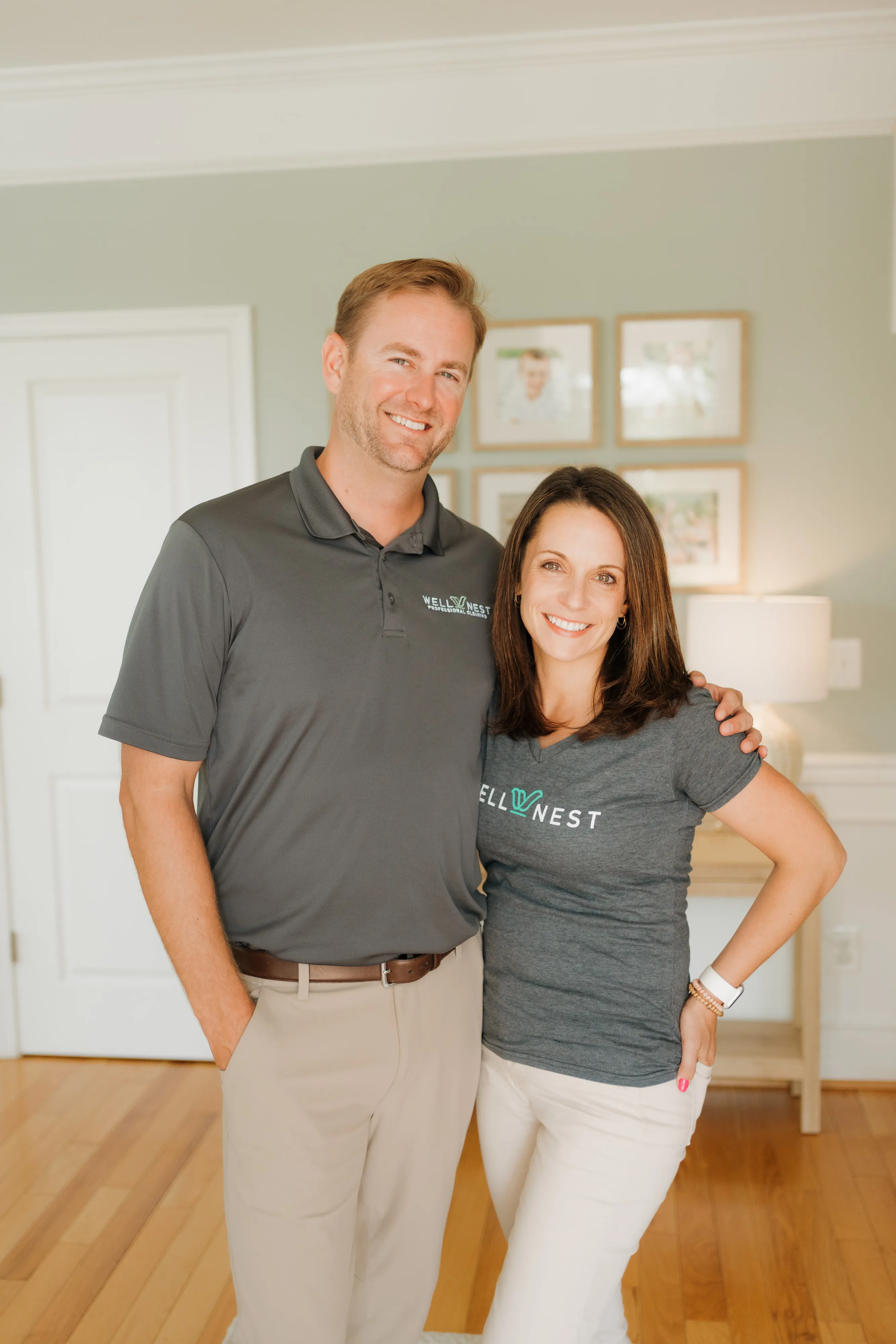 Phil and Nicole Harper, founders of WellNest Professional Cleaning, smiling together in WellNest shirts at home
