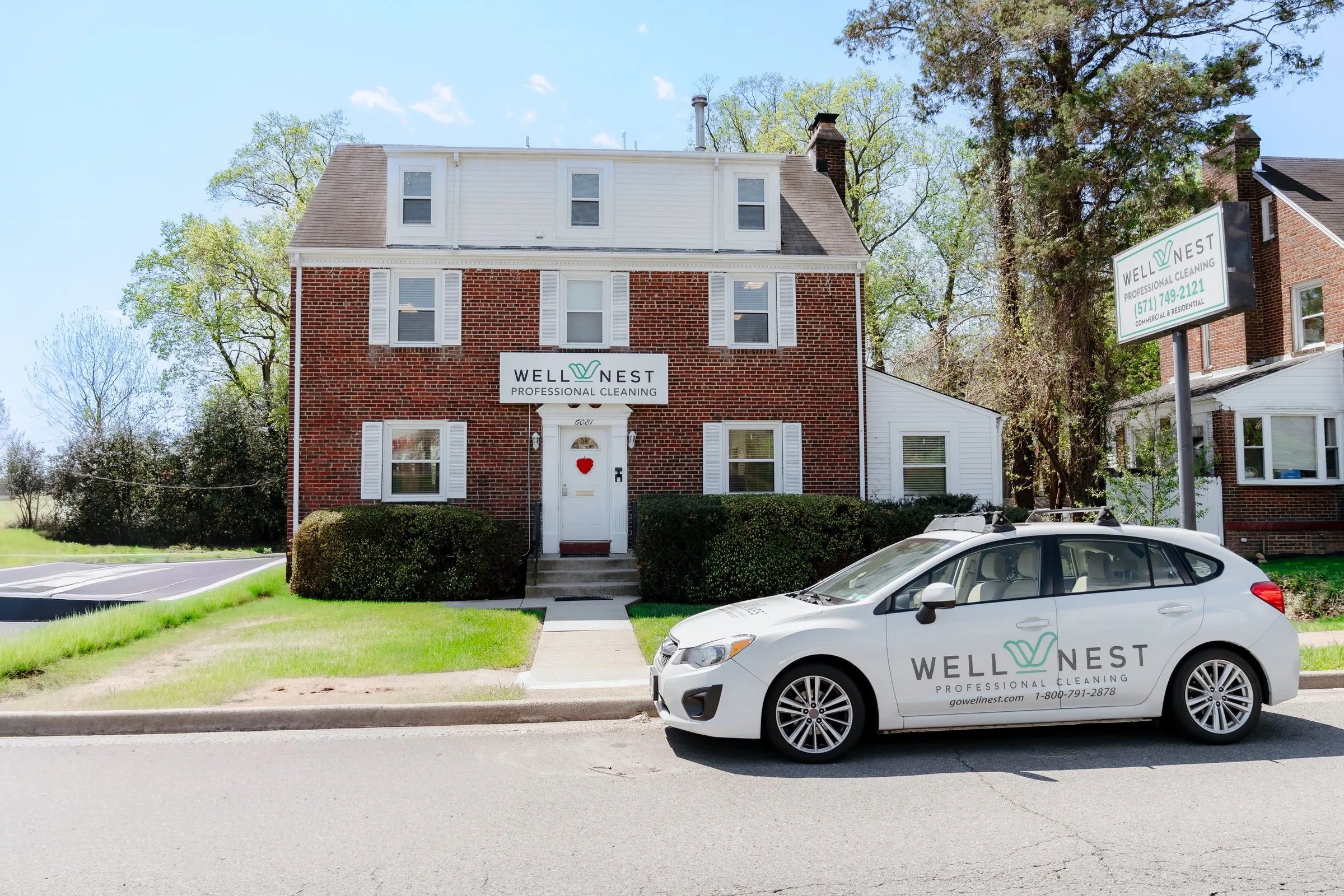WellNest's office in Falls Church, VA: a brick three-story building with the WellNest Professional Cleaning sign over the entrance and a branded company car parked out front.