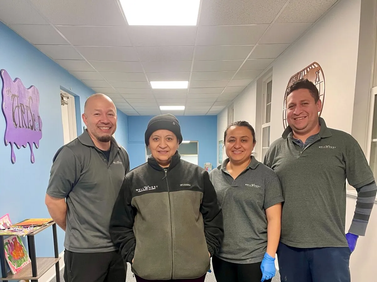 Four WellNest team members in branded uniforms standing together inside a Northern Virginia facility on their cleaning route